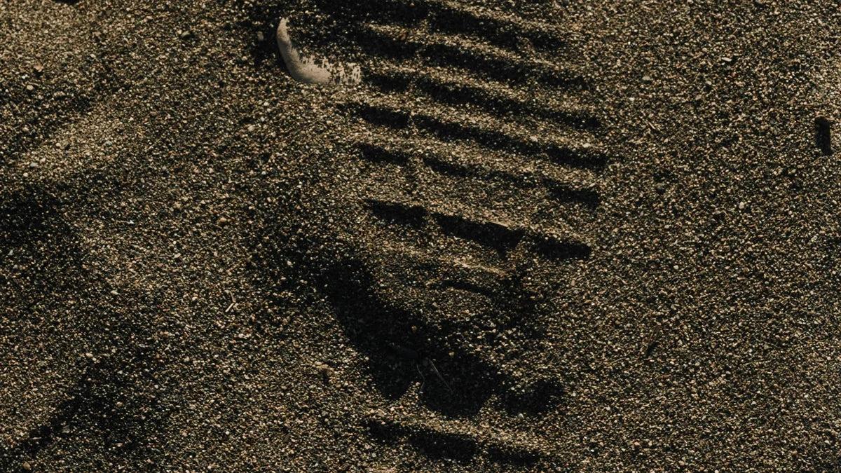Empreinte de semelle nette dans le sable, relief marqué par la lumière rasante