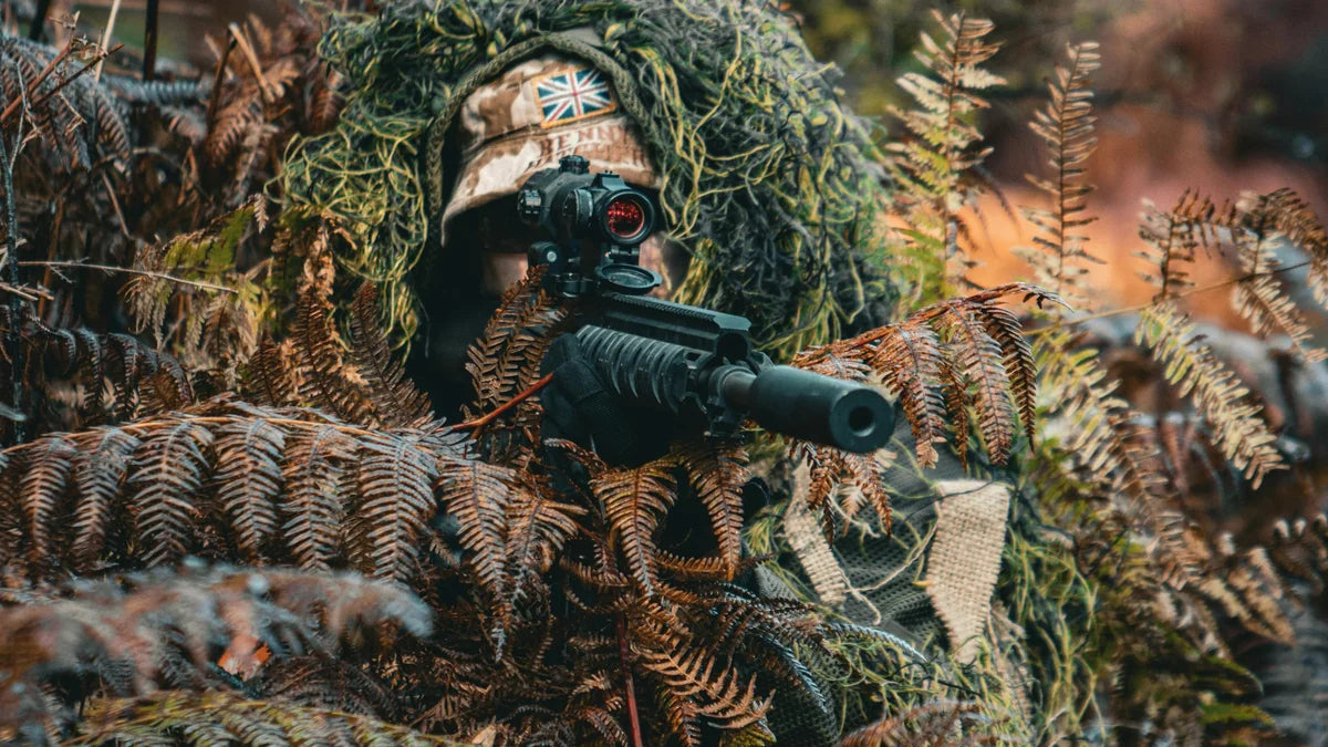 Sniper en ghillie suit dissimulé dans les fougères, position de tir : dissimulation tactique