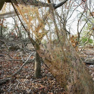 Bâche de camouflage militaire tendue entre les arbres en sous-bois